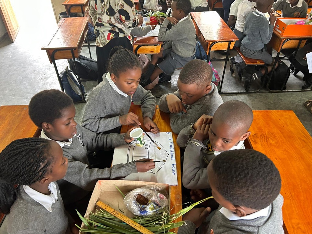 A group of children working on a drawing during a visit from The Blue Coat School Birmingham to establish The Blue Coat Malawi Project