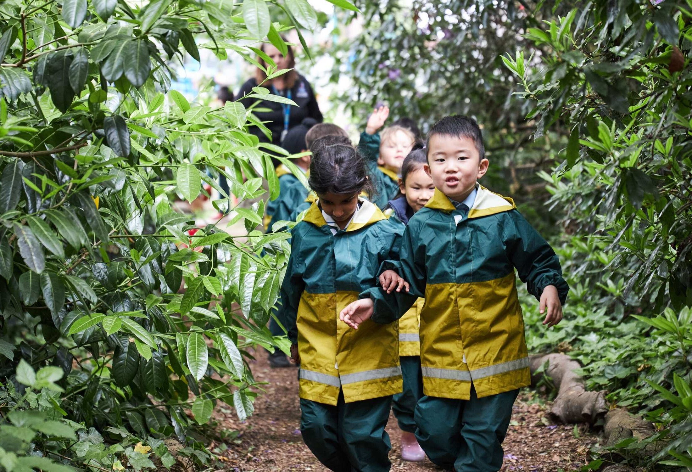Children walking through the trees in Forest School.