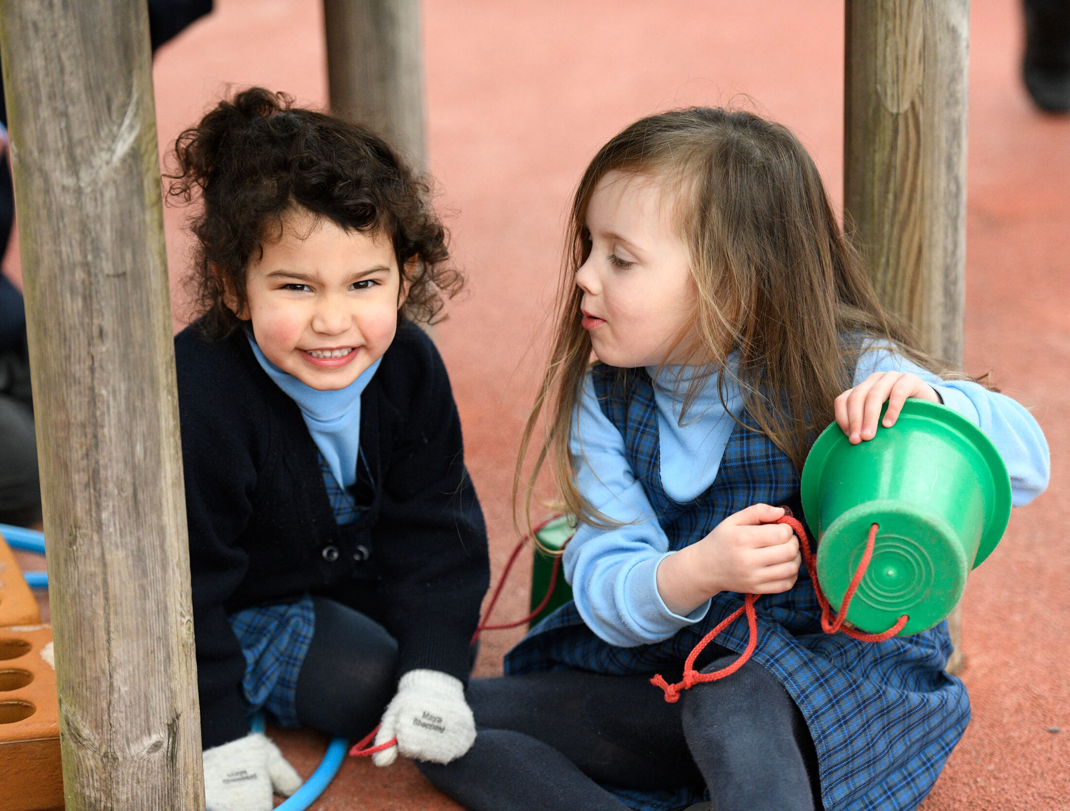 Two Nursery girls playing with a bucket in the playground at The Blue Coat School.