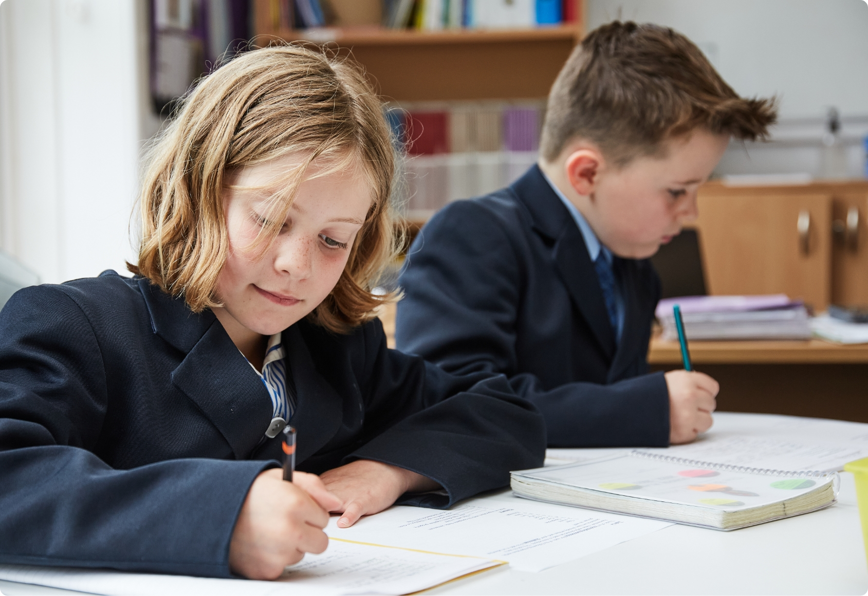 Two pupils are writing in their books at school.