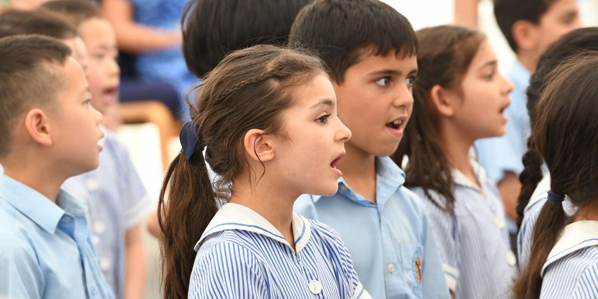 A group of children are singing in assembly