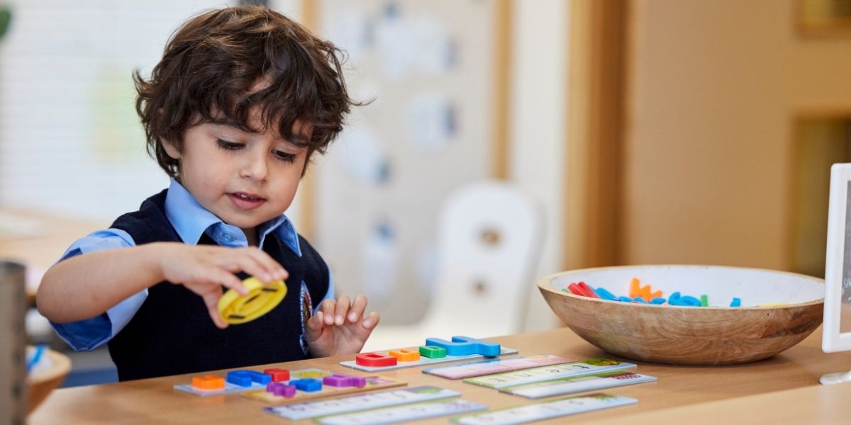 A boy in Nursery Pre-Prep matches letter magnets to the written letters.