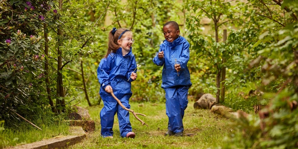 A boy and a girl are laughing with each other in Forest School